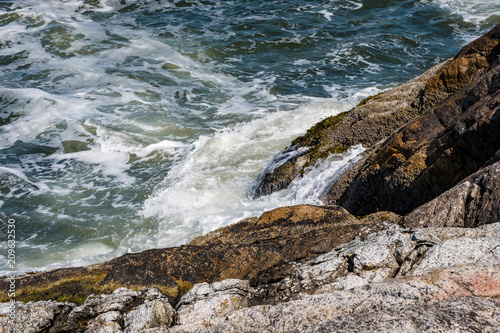 wave pounding the shore rocks under the sun © Yi