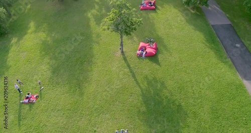 Aerial view of people relaxing on the fresh green lawn in the park on a warm summer day. Leisure activity, lifestyle concept.