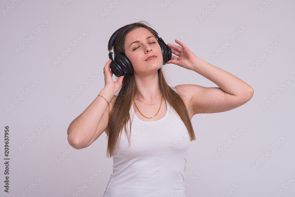 portrait of a beautiful brunette girl on a white background in headphones listening to music portrait of a beautiful brunette girl on a white background in headphones listening to music