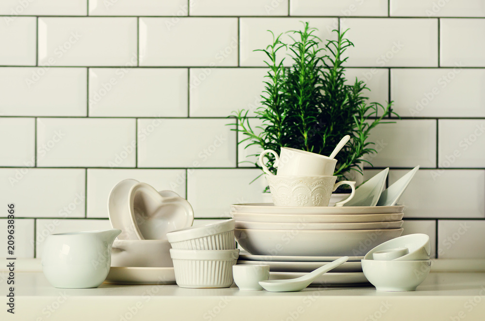 White tableware for serving. Dishes, cups, spoons, utensils and other different white stuff on table-top. Kitchen accessories. Copy space. Minimal and clean concept White tableware for serving. Dishes, cups, spoons, utensils and other different white stuff on table-top. Kitchen accessories. Copy space. Minimal and clean concept