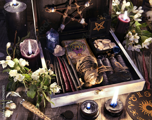 Witch box with black candles, tarot cards, runes, voodoo doll and magic objects with flowers Occult, esoteric and divination still life. Halloween background with vintage objects and magic ritual