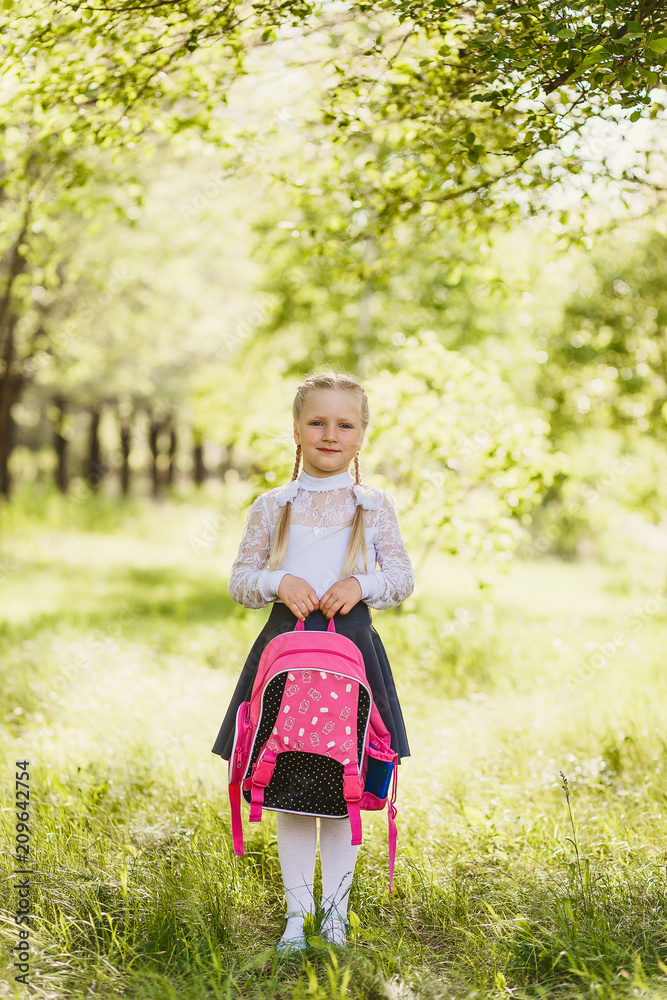 first-grader girl stands with a school pink backpack outdoors first-grader girl stands with a school pink backpack outdoors