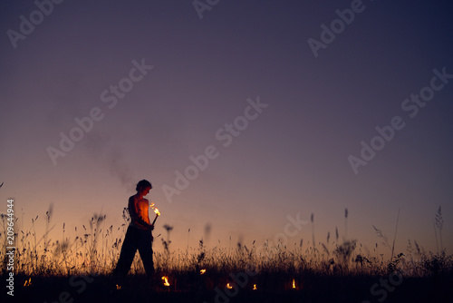 A man with a torch at sunset. Fire show and a lot of the bright sparks in the night