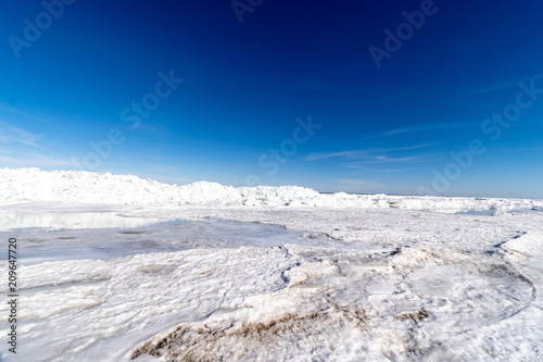 frozen lake covered with stack of ice floes and blue sky