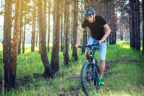 Man in a helmet riding on a mountain bike in the woods. Cyclist in motion. Concept of active and healthy lifestyle