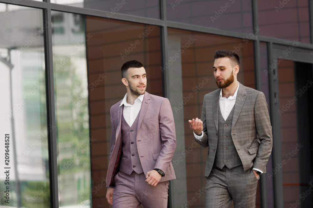 Two smiling young businessmen walking and talking in the city Two smiling young businessmen walking and talking in the city