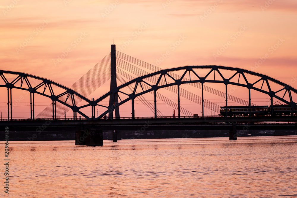 railroad metal bridge silhouette over river of Daugava in Riga, Latvia in dark red sunet railroad metal bridge silhouette over river of Daugava in Riga, Latvia in dark red sunet
