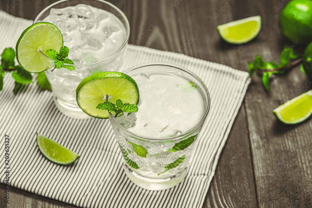 Fresh lime cocktail with ice cubes on wooden background Fresh lime cocktail with ice cubes on wooden background