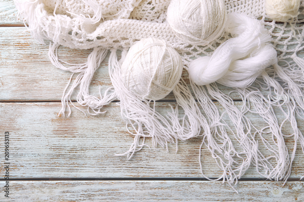 Balls of knitting yarn with scarf on wooden background Balls of knitting yarn with scarf on wooden background
