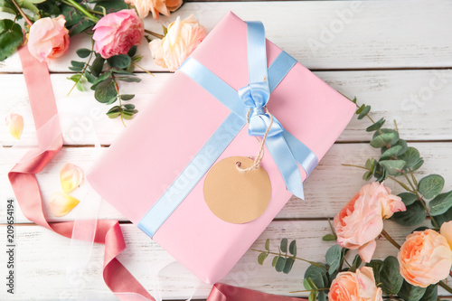 Beautiful flowers and gift box on wooden background