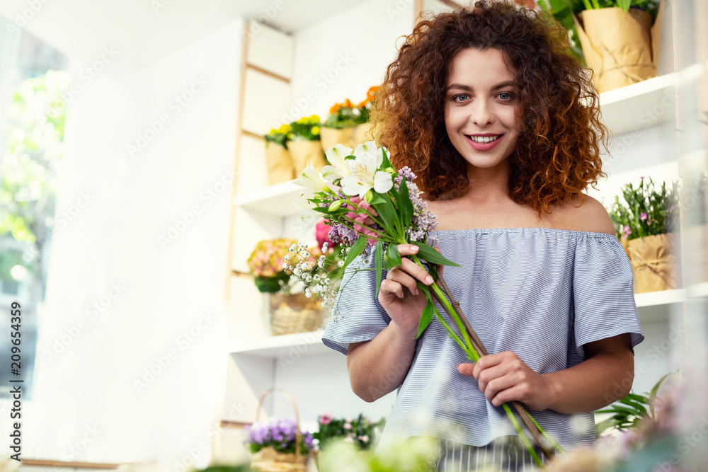 For a gift. Positive joyful woman buying flowers while visiting a flower shop