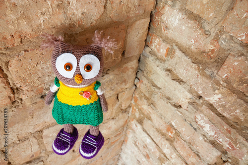 Handmade toy owl on a brick wall background photo