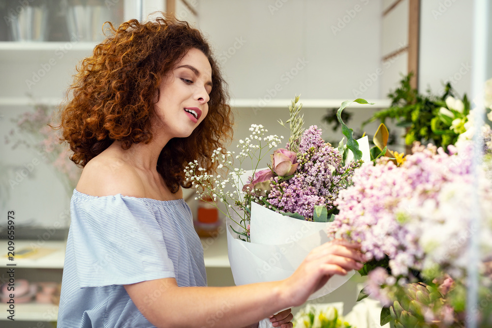 So tender. Nice pleasant woman touching flowers while being in the flower shop