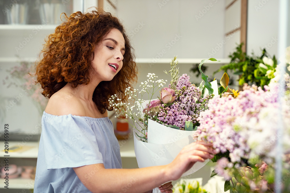 So tender. Nice pleasant woman touching flowers while being in the flower shop So tender. Nice pleasant woman touching flowers while being in the flower shop