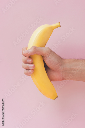 hand holding Banana isolated on pink background.