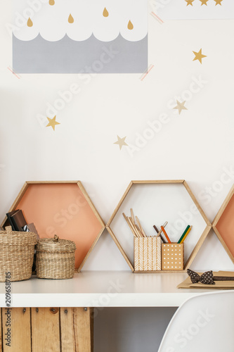 Close-up of a desk with pen cups, shelves in the shape of honeycombs and star stickers on the wall