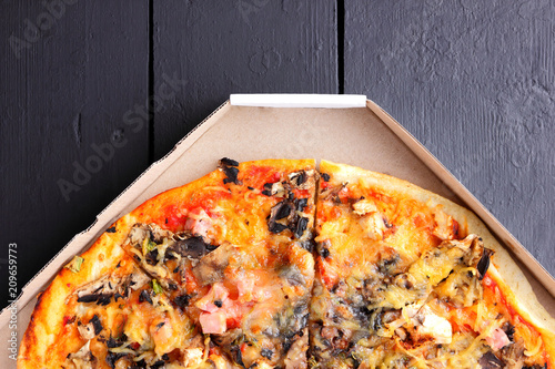 Pizza with chicken, mushrooms and cheese on black boards, pizza felicita in a cardboard box top view, Italian food, appetizing dish for summer holidays, American food, copy space