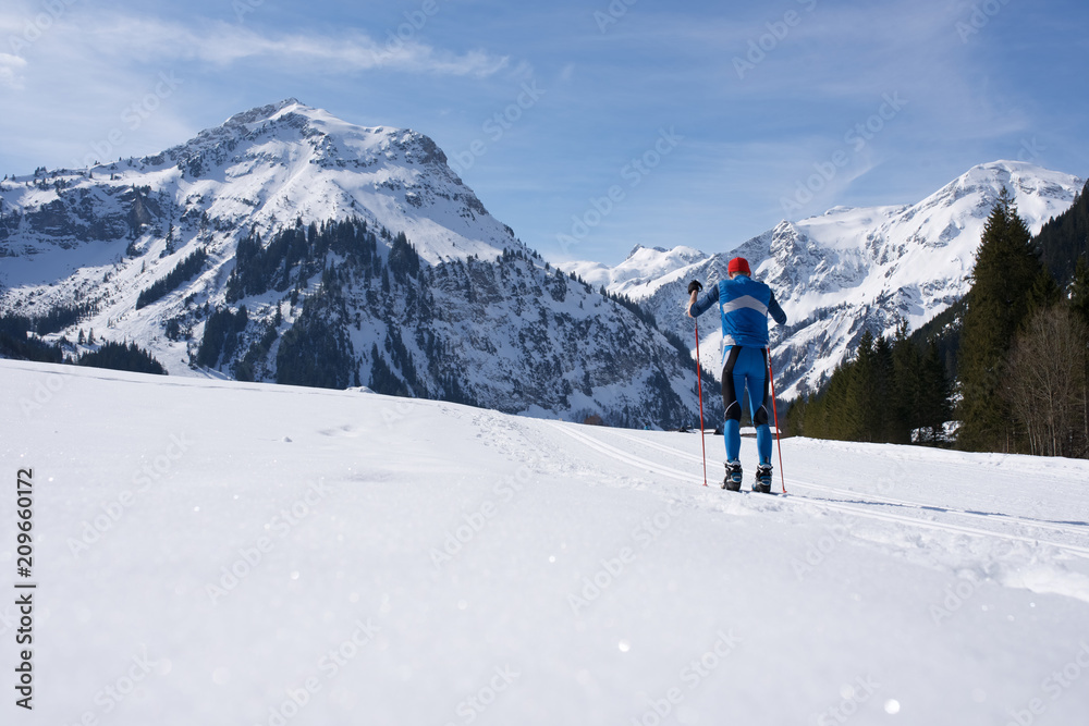 Skilangläufer vor Alpenbergen im Winter beim Skifahren5