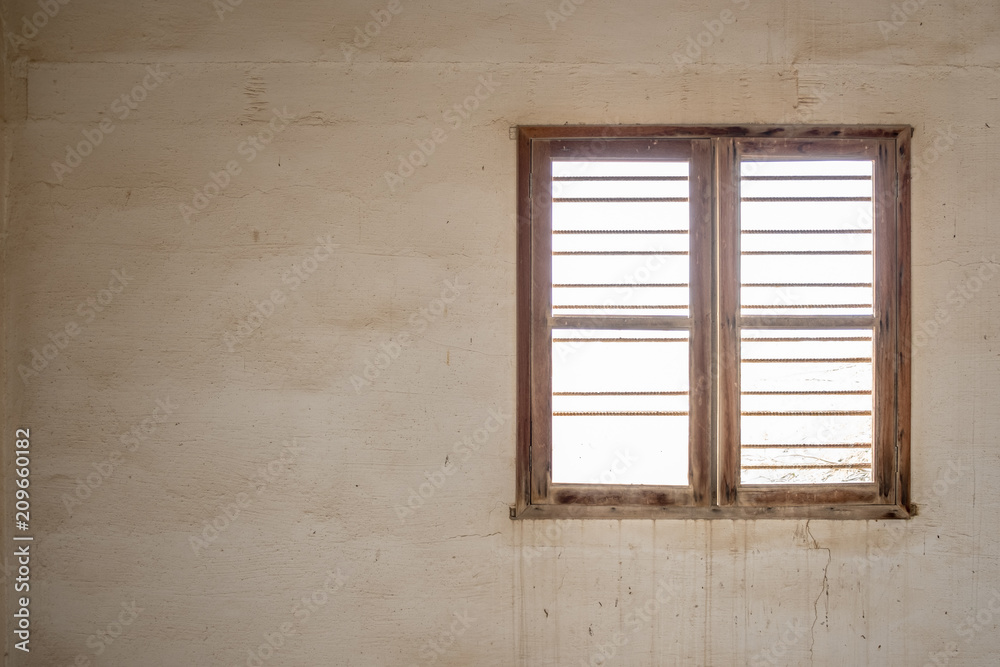 A glassless, barred window in the wall of a room in an abandoned, derelict building with stained walls. A glassless, barred window in the wall of a room in an abandoned, derelict building with stained walls.