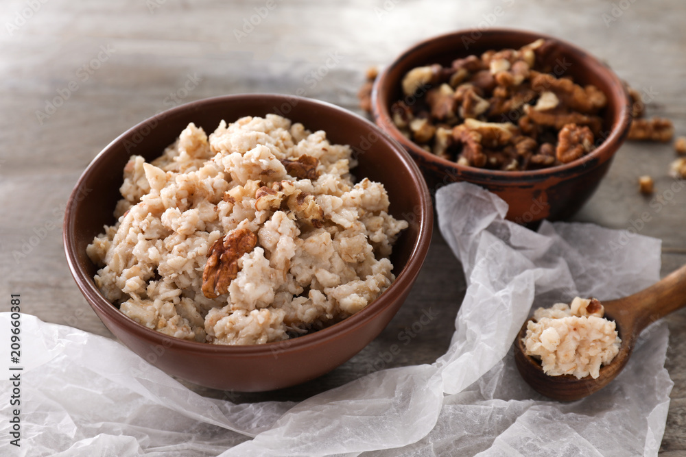 Bowls with tasty oatmeal and walnuts on wooden table Bowls with tasty oatmeal and walnuts on wooden table