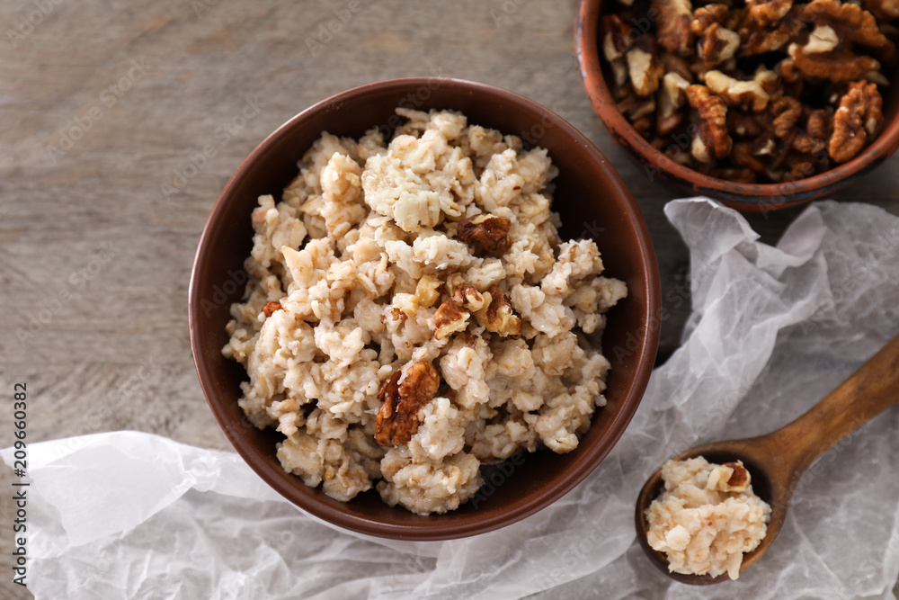 Bowl with tasty oatmeal and walnuts on wooden table Bowl with tasty oatmeal and walnuts on wooden table