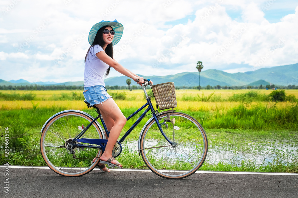woman traveler enjoying for view of rice field. Asian lady tourist riding a bicycle and looking for view of nature on holiday. woman traveler enjoying for view of rice field. Asian lady tourist riding a bicycle and looking for view of nature on holiday.