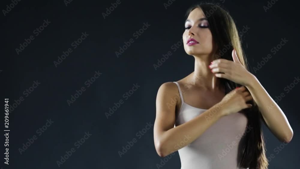 Slim young woman with long hair in studio on black background. Slim young woman with long hair in studio on black background.