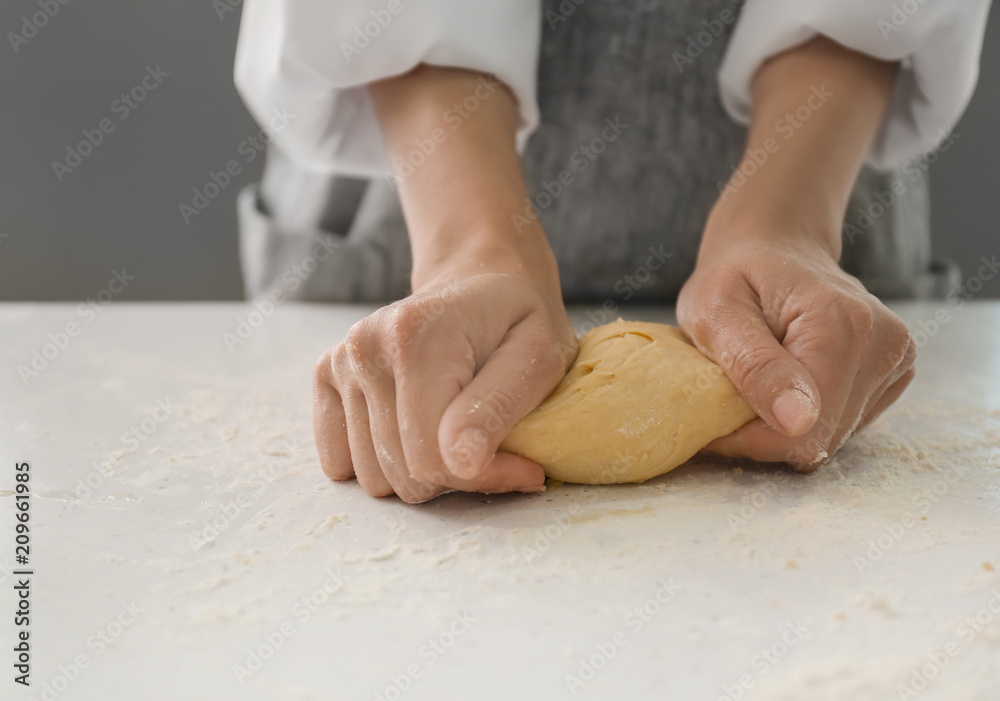 Obraz premium Woman kneading dough for bakery on kitchen table