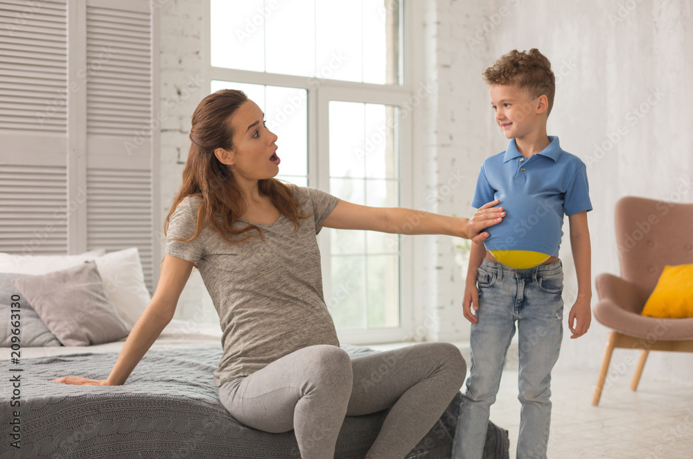 Cheer up. Beautiful loving pregnant mother wearing grey shirt and leggings feeling amazing while cheering up her son Cheer up. Beautiful loving pregnant mother wearing grey shirt and leggings feeling amazing while cheering up her son