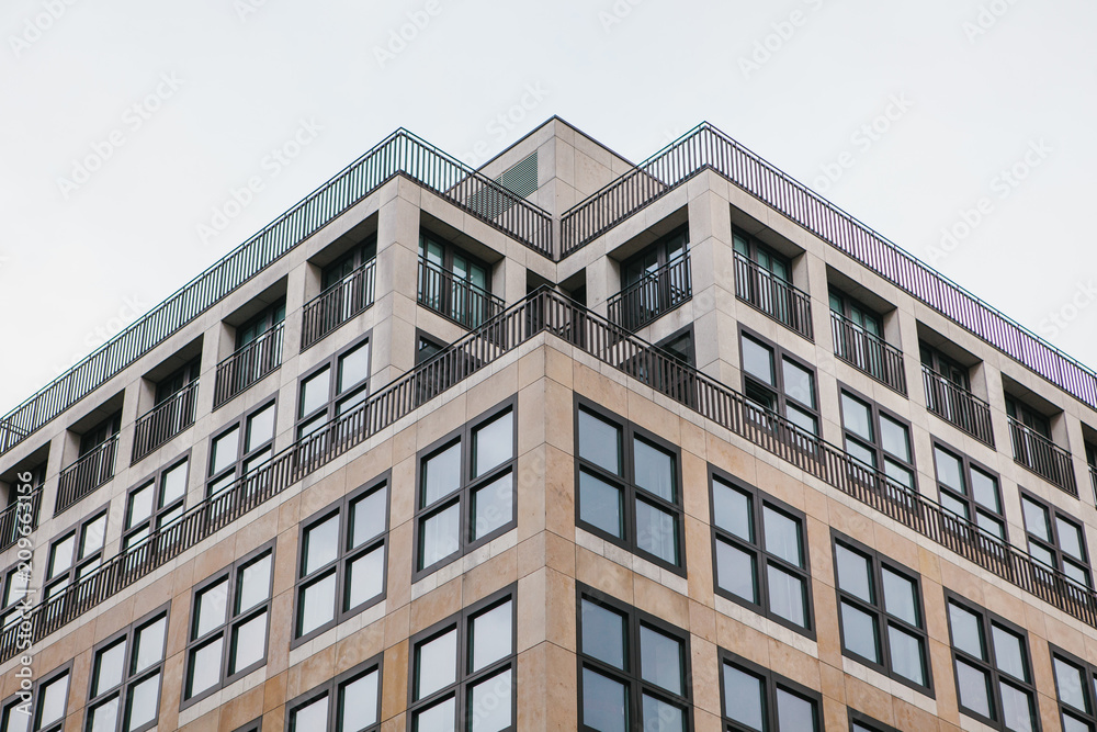 A symmetrical snapshot of a building corner with lots of windows against the sky