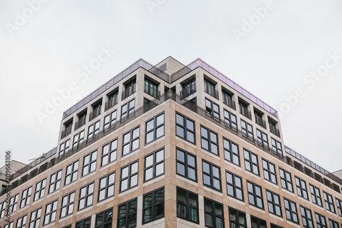 A symmetrical snapshot of a building corner with lots of windows against the sky