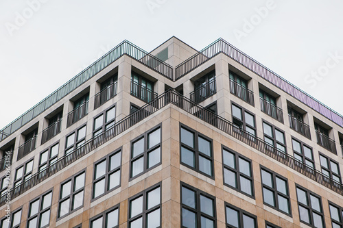 A symmetrical snapshot of a building corner with lots of windows against the sky photo
