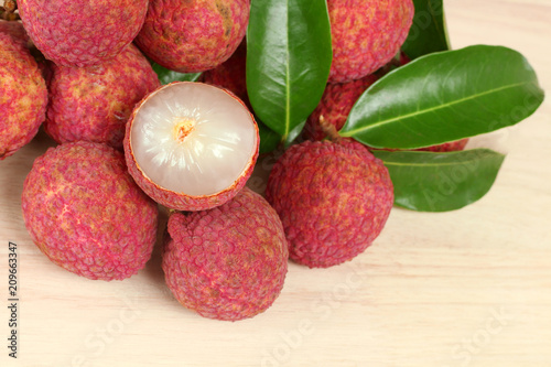 Fresh red lychee and peeled with leaves on wooden background with copy space.