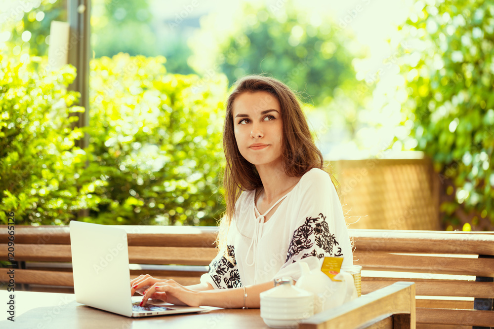 Beautiful attractive woman at the cafe with a laptop having a coffee break Beautiful attractive woman at the cafe with a laptop having a coffee break