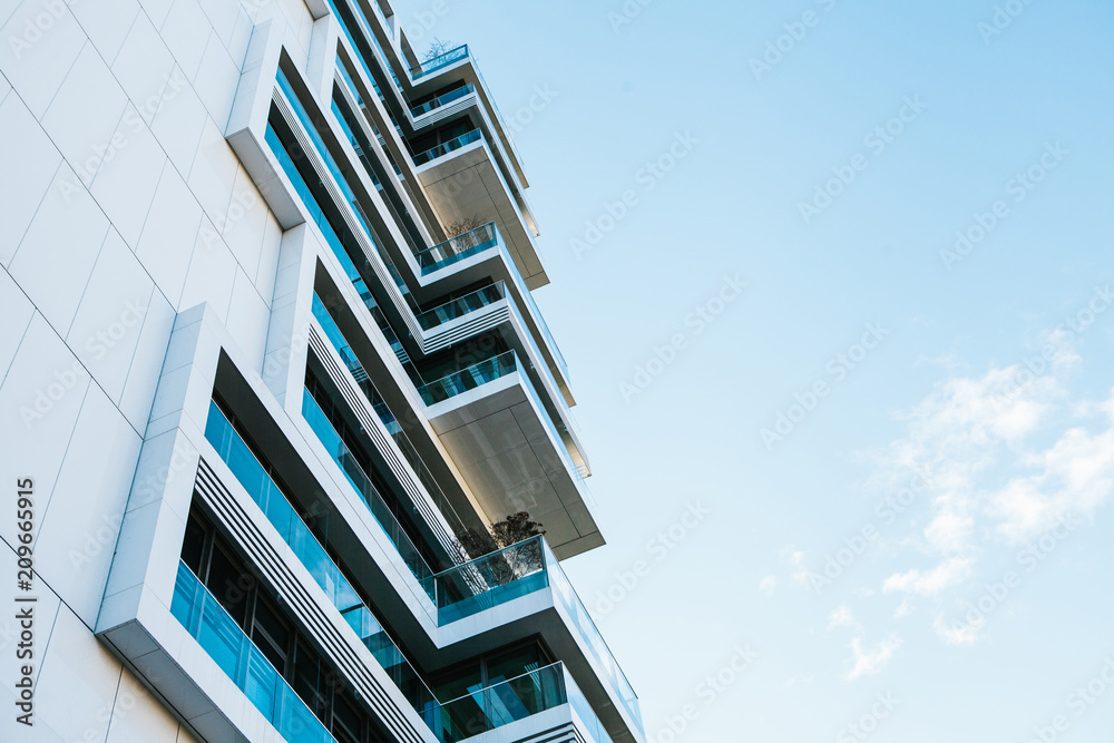 The corner of the building with many windows against the blue sky - obrazy, fototapety, plakaty 
