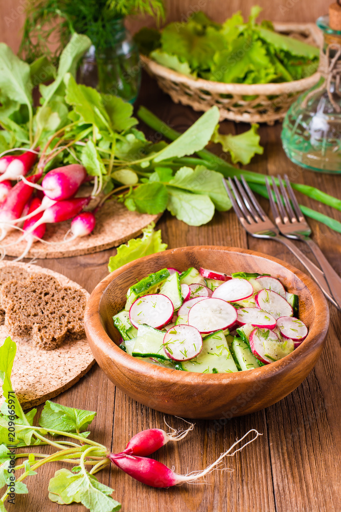 Lenten spring vegetable salad from cucumber, radish, greens and oil in a wooden plate Lenten spring vegetable salad from cucumber, radish, greens and oil in a wooden plate