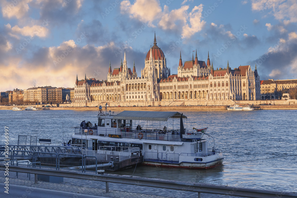 view of the tourist ship on the Danube against the Parliament building and the beautiful evening sky