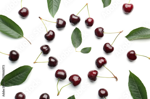 Composition with sweet cherries and green leaves on white background