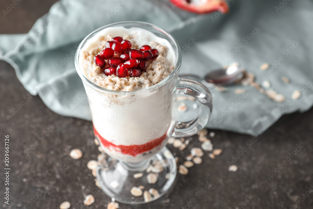 Tasty oatmeal dessert with fresh pomegranate seeds in glass cup on table Tasty oatmeal dessert with fresh pomegranate seeds in glass cup on table