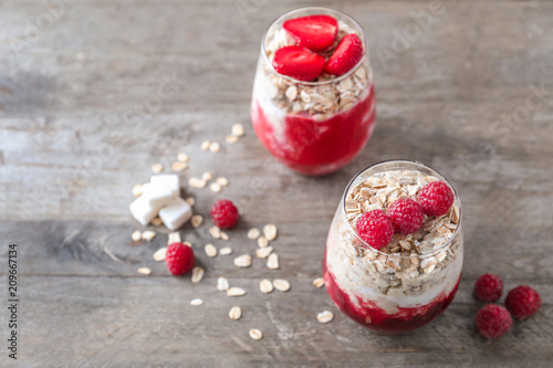 Delicious oatmeal desserts with fresh raspberries in glasses on wooden table