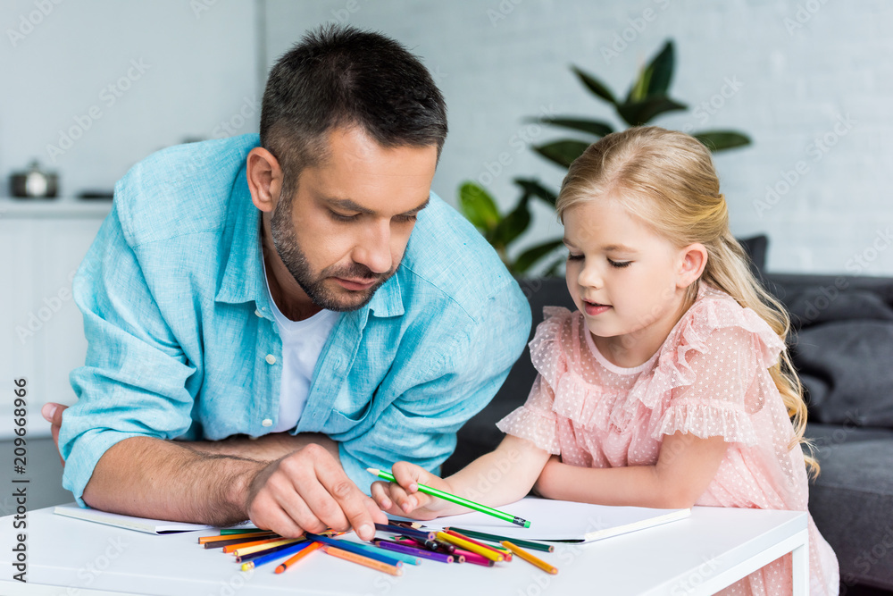 father and daughter drawing with colored pencils together at home father and daughter drawing with colored pencils together at home