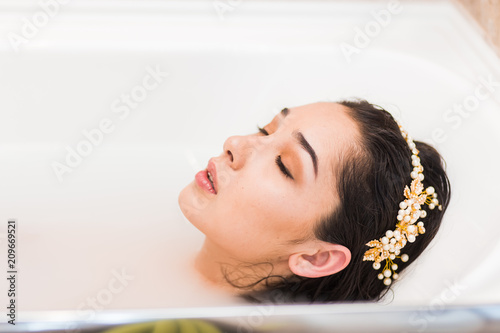Close up woman face profile with decoration on the head lying in a bath