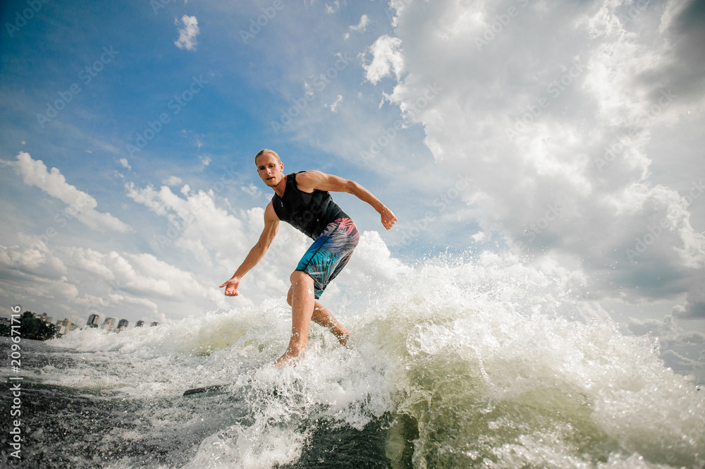 Young attractive man riding on the wakeboard