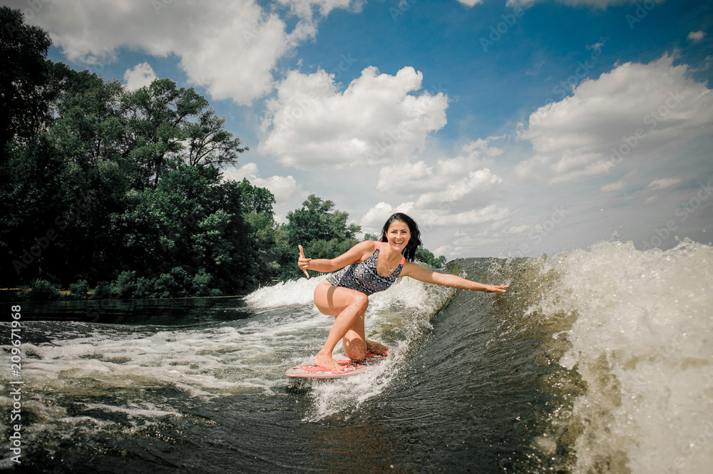 Young attractive woman riding on the wakeboard