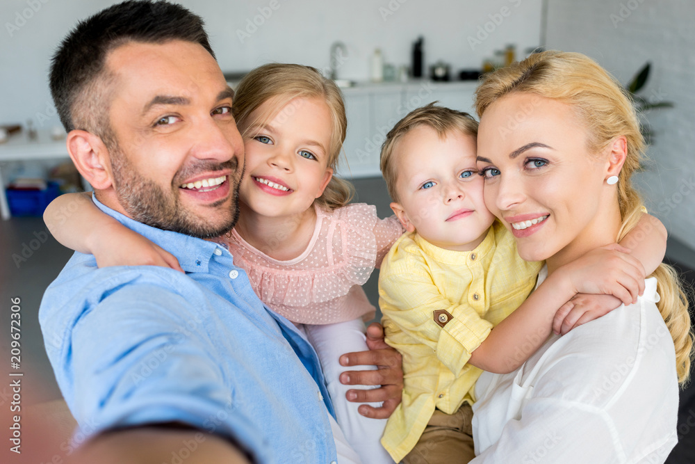 Fototapeta premium happy family with two kids hugging and smiling at camera at home