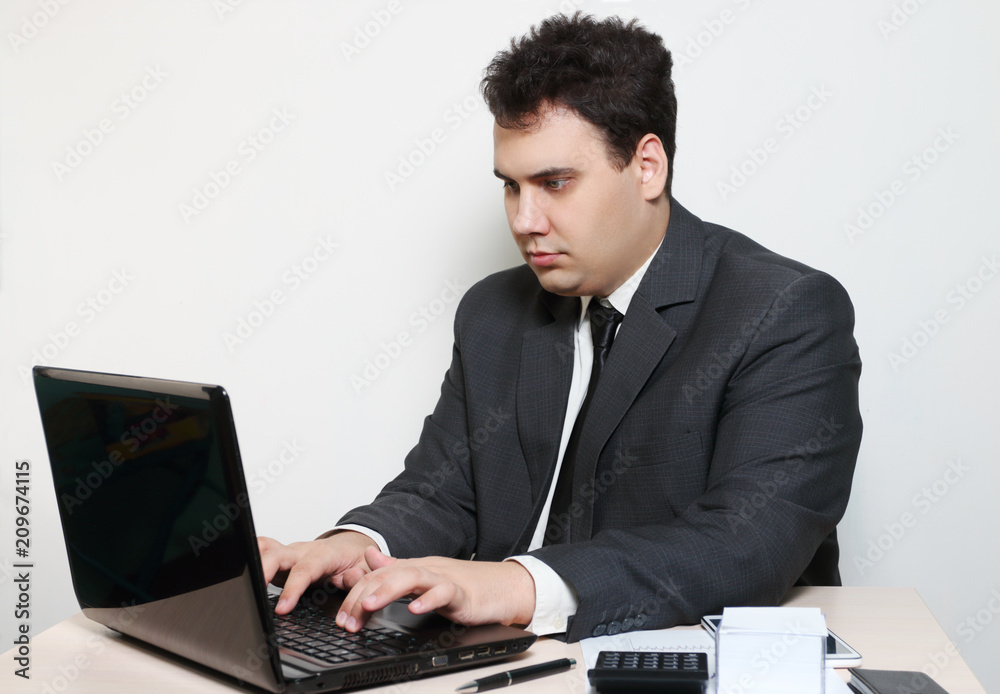 Businessman in suit works with laptop at table with paper, pen, calculator Businessman in suit works with laptop at table with paper, pen, calculator