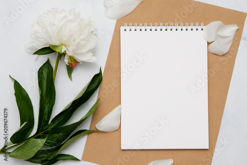 Composition with flowers and notebook on white background. Mock up for your design. Flat lay.