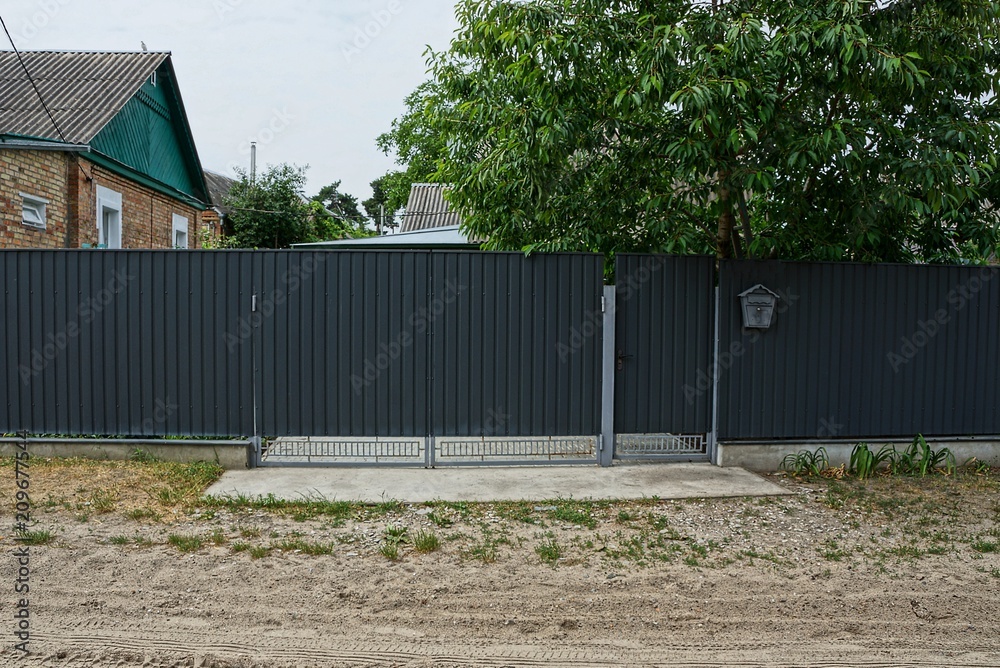 a long gray metal fence and closed gates on the street a long gray metal fence and closed gates on the street