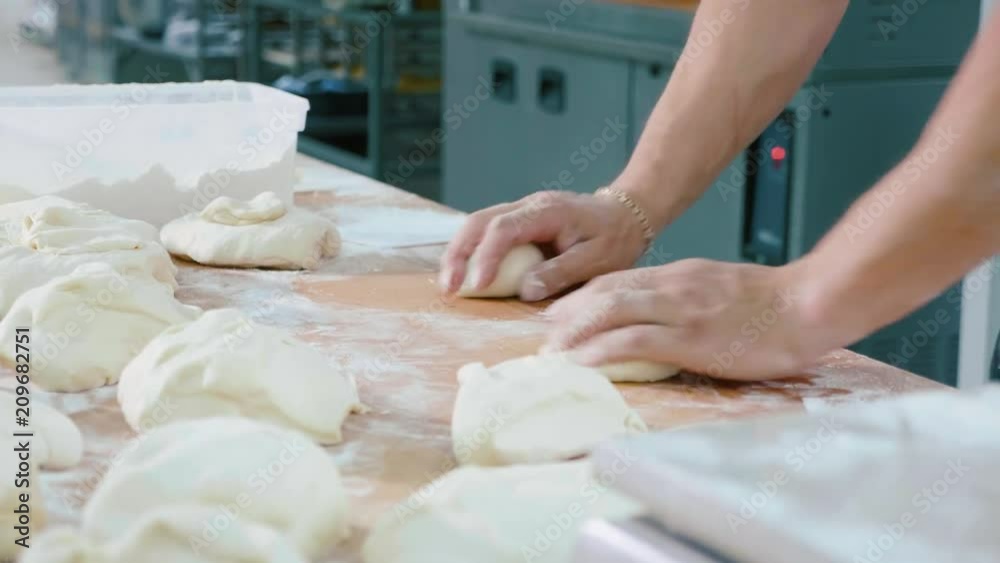 Professional baker is forming pieces of dough in bakery commercial kitchen. Professional baker is forming pieces of dough in bakery commercial kitchen.