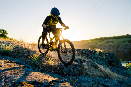 Cyclist Riding the Mountain Bike on the Summer Rocky Trail at the Evening. Extreme Sport and Enduro Cycling Concept.